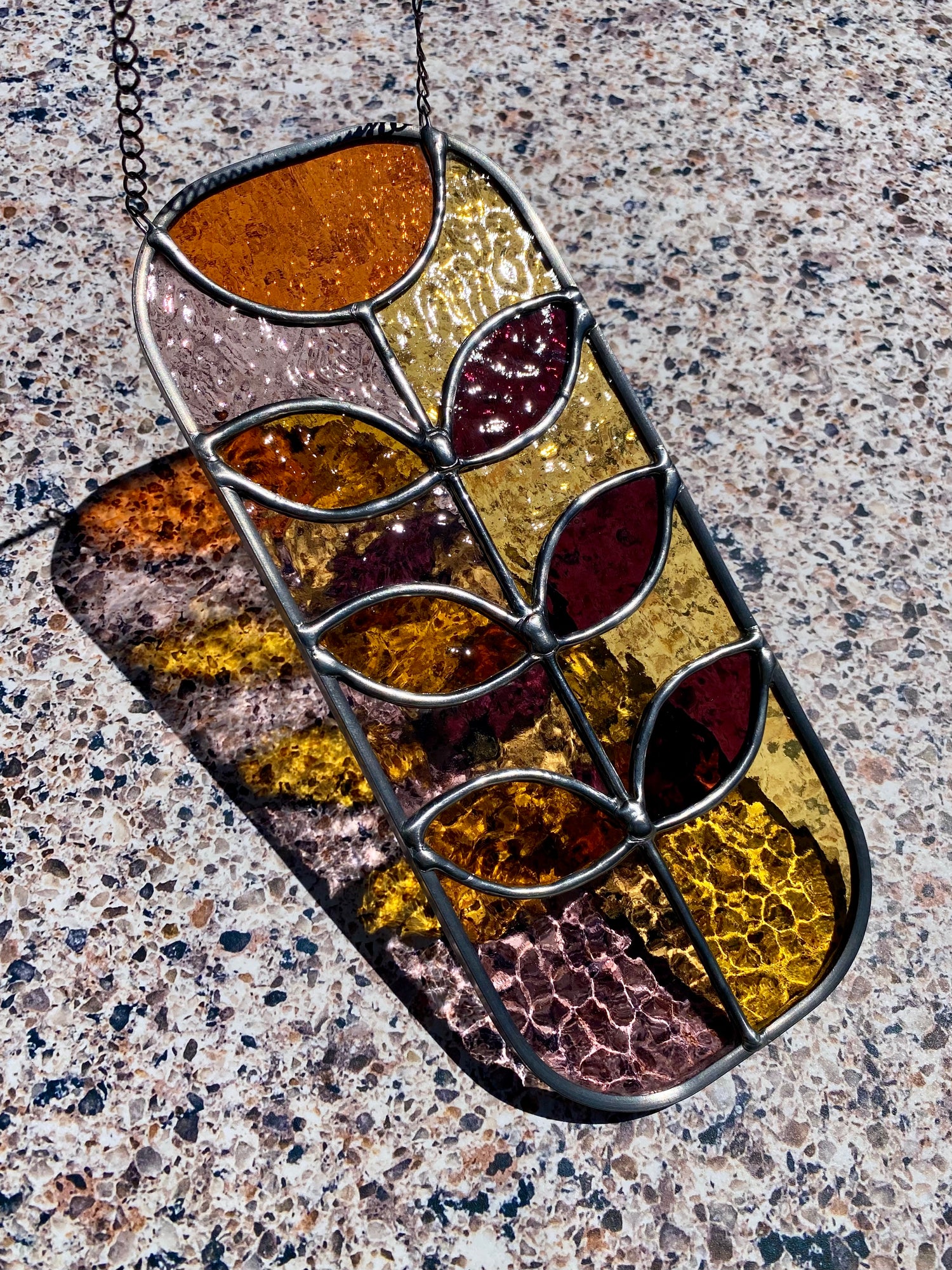 A stained glass panel featuring a contemporary floral design in an autumnal colorway on a textured background