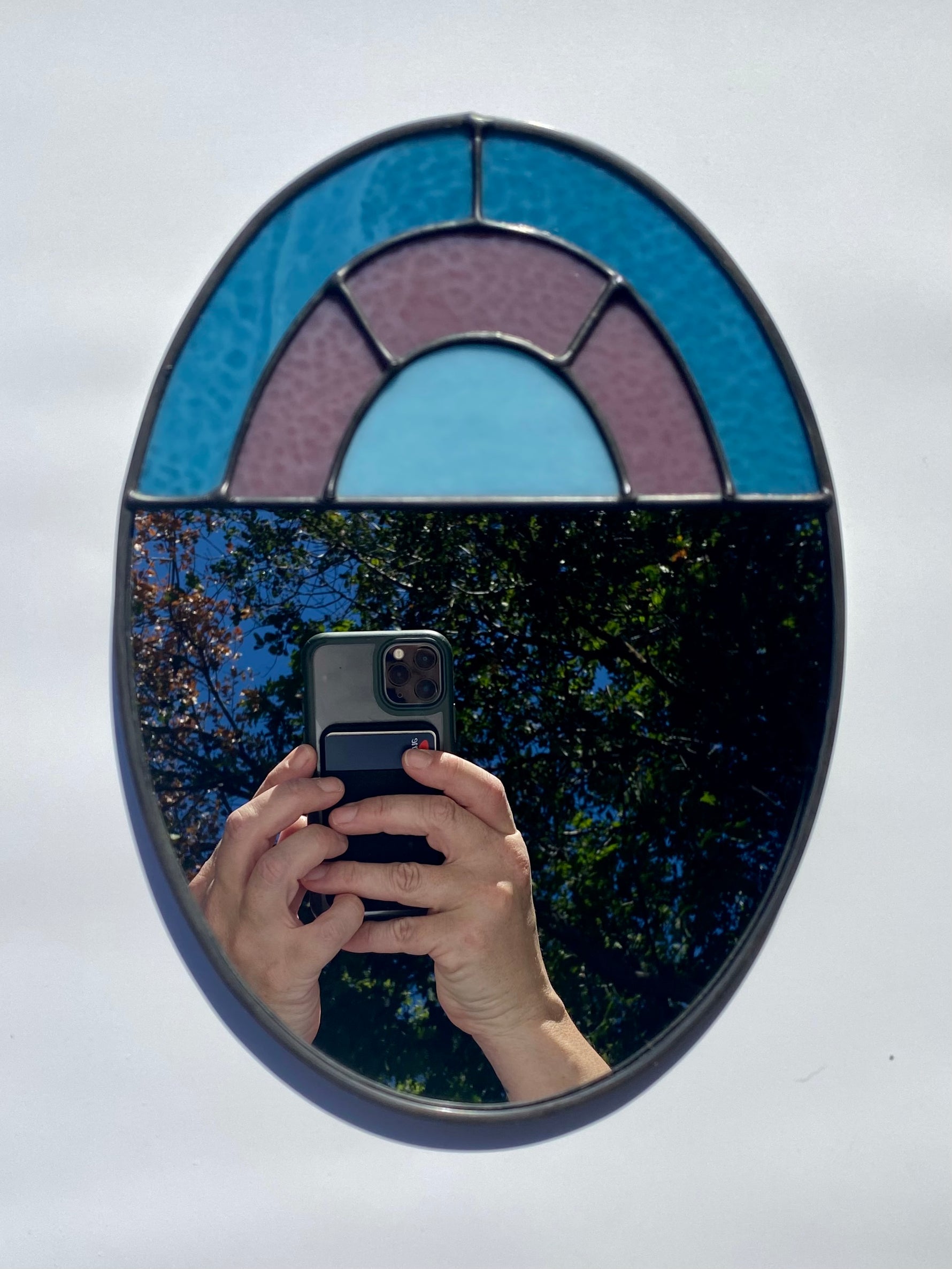 Stained glass decorative mirror with a muted arch design.