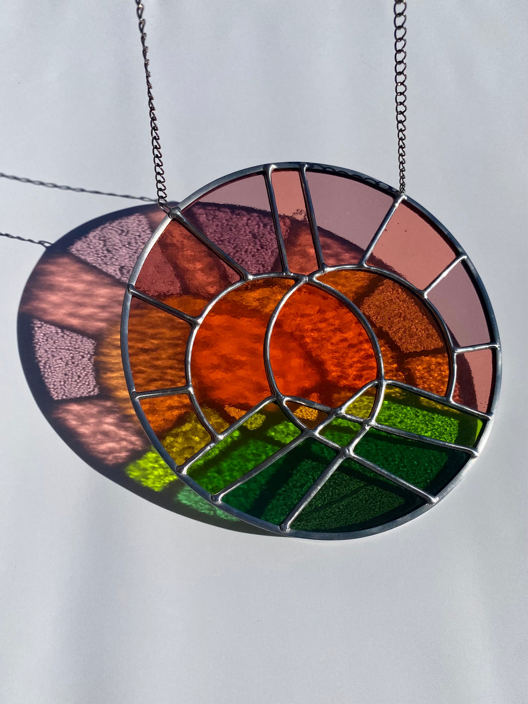 Stained glass sun catcher with a landscape design on a white background