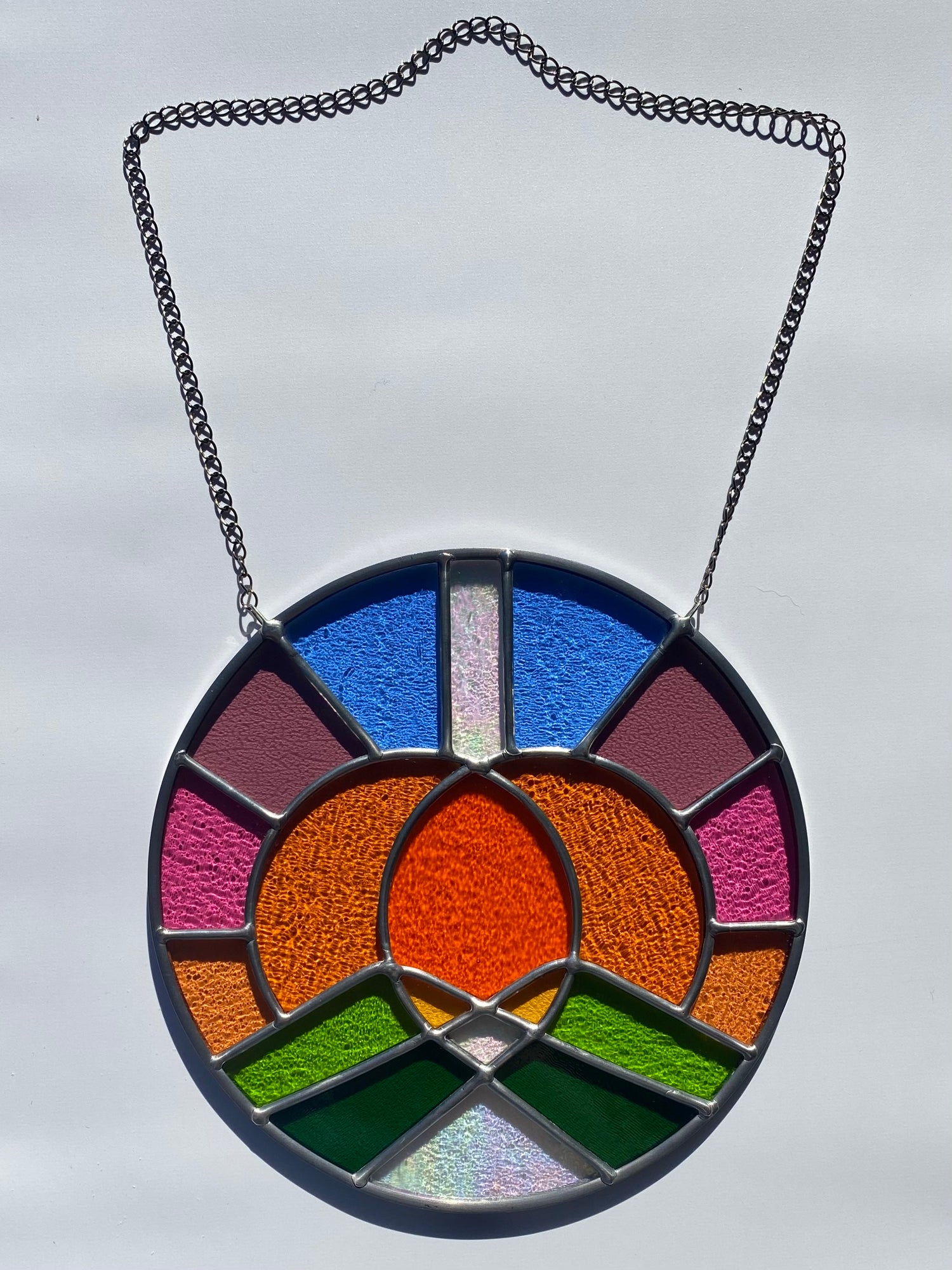 Stained glass panel with colorful circular design on a white background