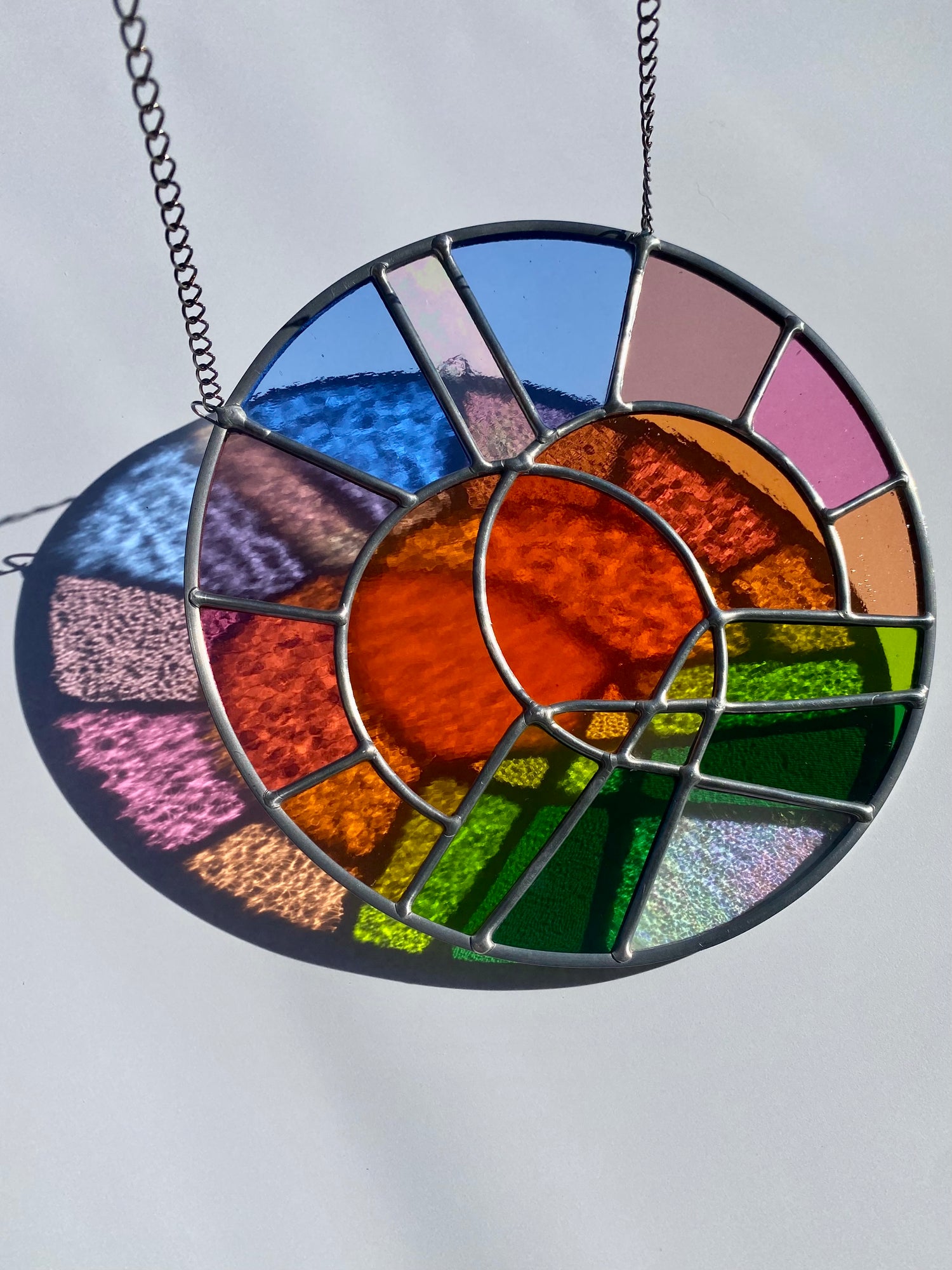 Stained glass suncatcher with colorful circular design on a plain background