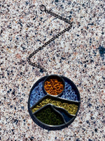Round stained glass sun catcher with a landscape design against a textured background